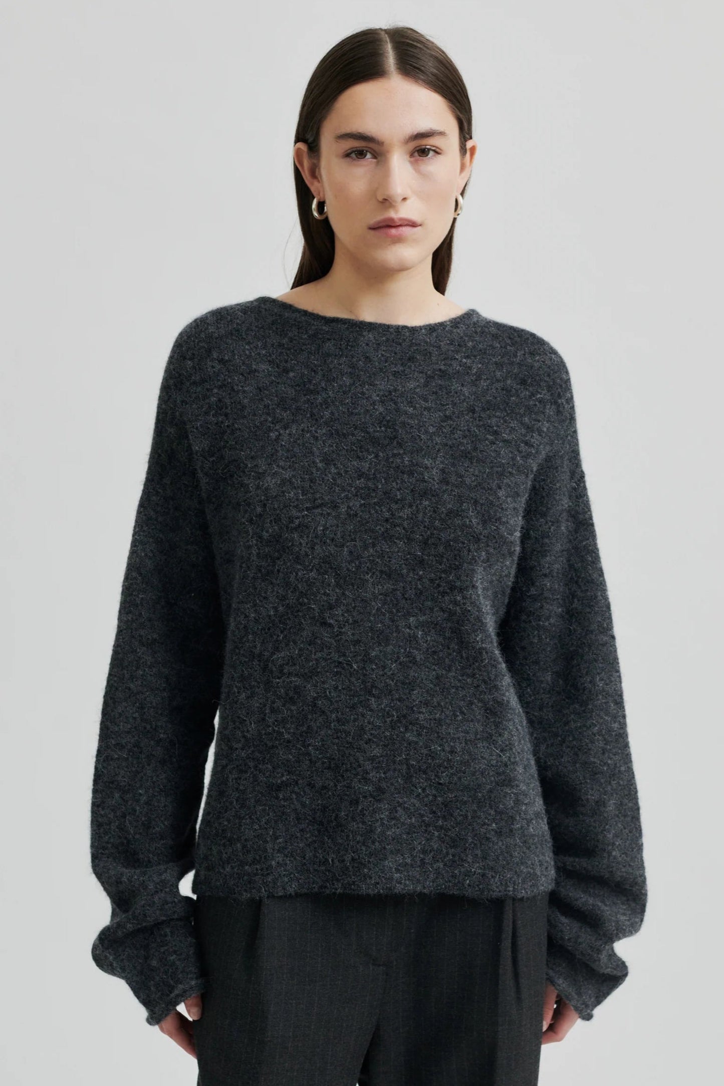 Person wearing a dark gray sweater on a light gray background